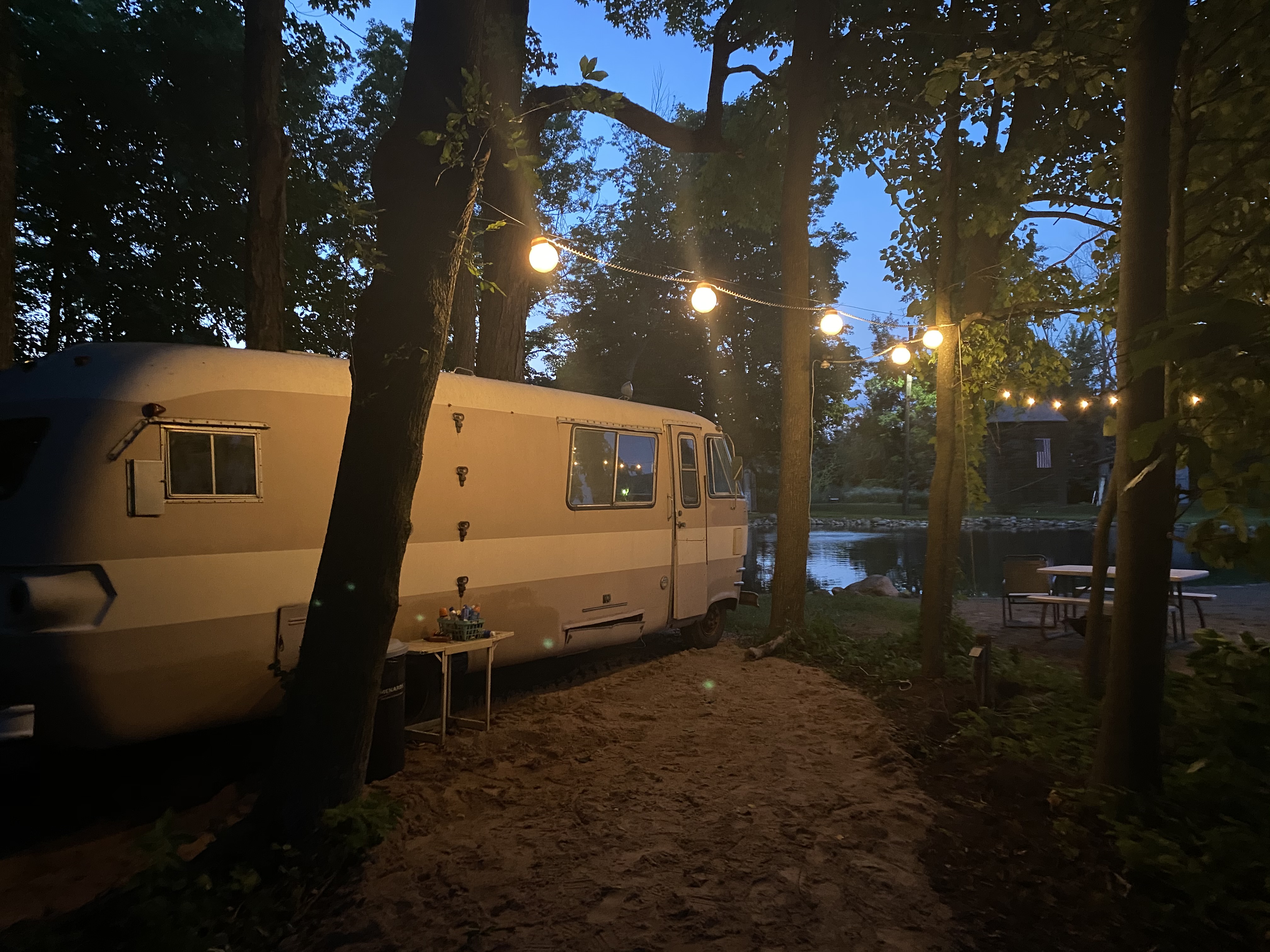 Motor home parked by pond with lights at night